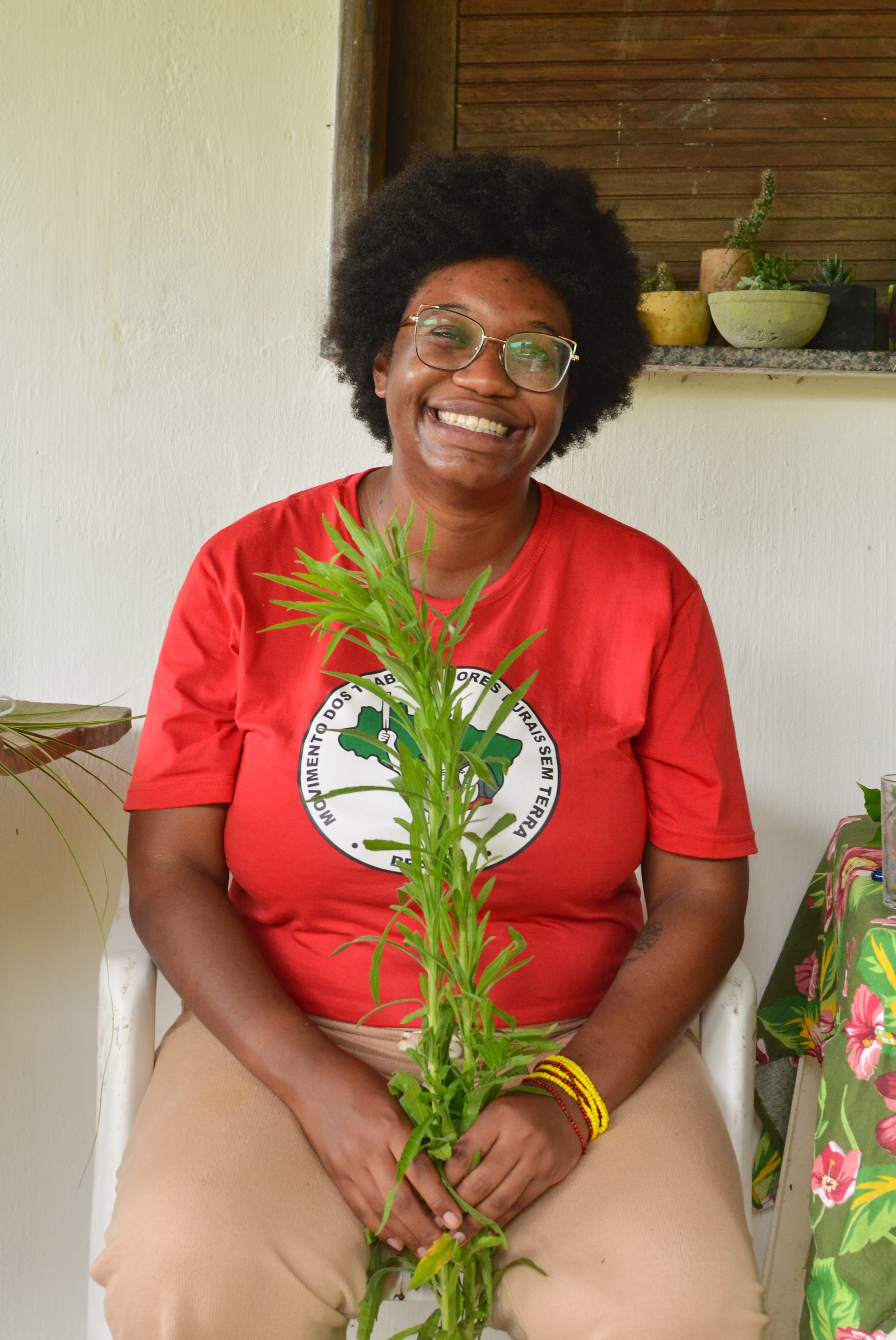 Bruna Crioula com camiseta do MST segurando planta
