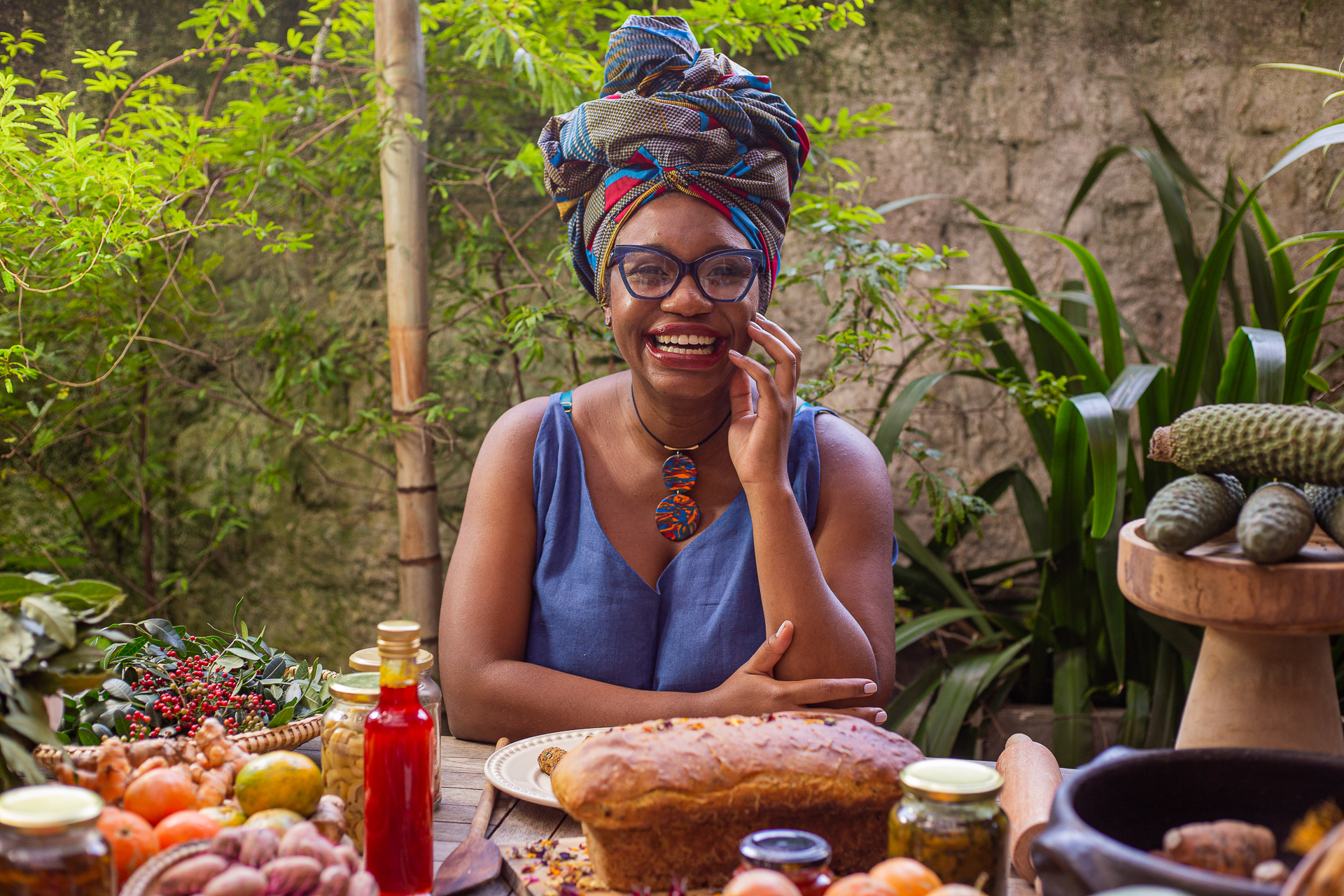 Bruna Crioula sorrindo à mesa de fartura com alimentos