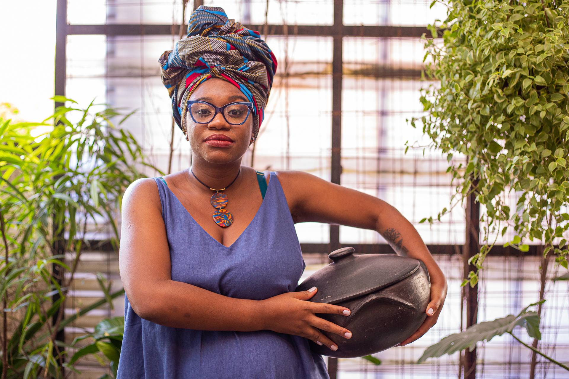Bruna Crioula segurando uma panela de barro, rodeada de plantas